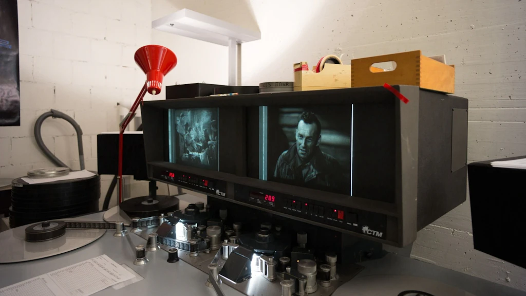 Postazione per il restauro e la digitalizzazione di pellicole con bobine, monitor e attrezzature tecniche in uno spazio della Cineteca svizzera.