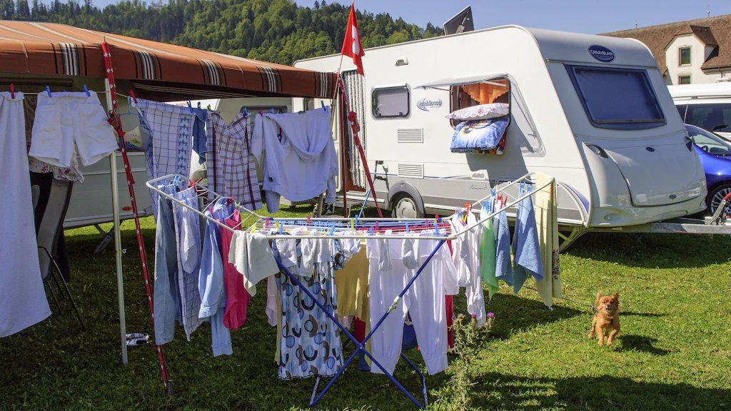 Wäsche hängt vor einem Wohnwagen auf einem Standplatz; Alltagsszene von Jenischen und Sinti in der Schweiz.