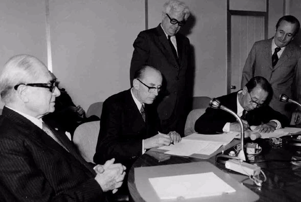 Die schwarz-weiss Fotografie zeigt René Maheu, den damaligen Generaldirektor der UNESCO bei der Unterzeichnung der Welterbekonvention 1972.
