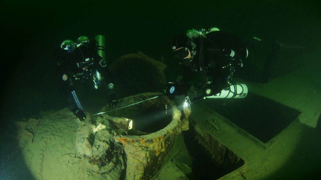 L’image montre deux plongeurs qui examinent et mesurent l’épave du vapeur Jura au fond du lac de Constance.