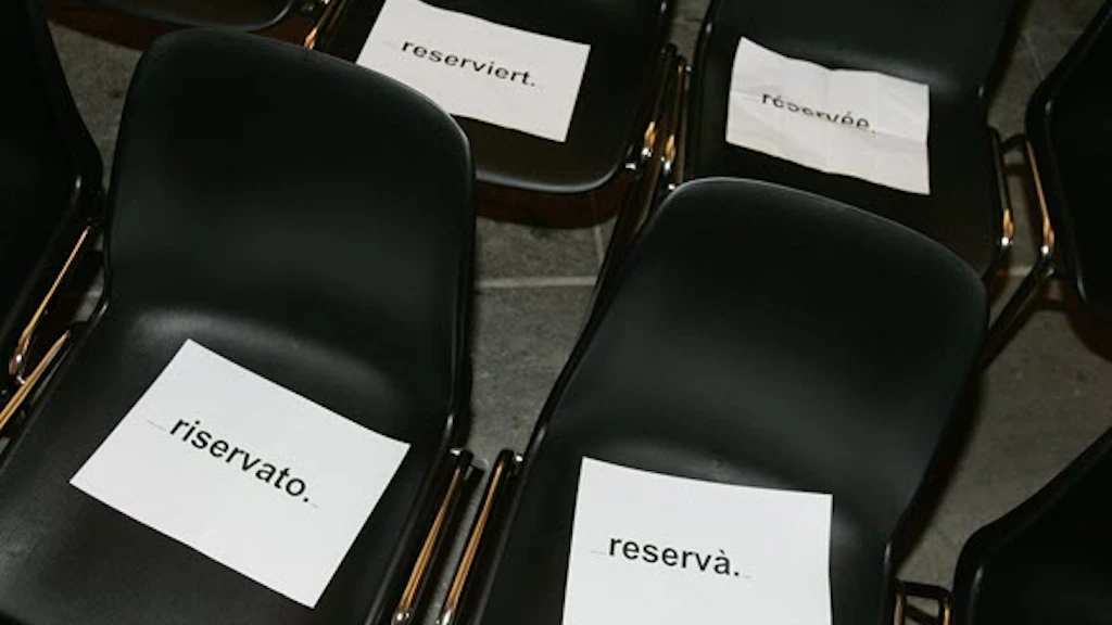 Plusieurs chaises noires avec des panneaux de réservation blancs dans les quatre langues nationales suisses : « reserviert », « réservée », « riservato » et « reservà ».