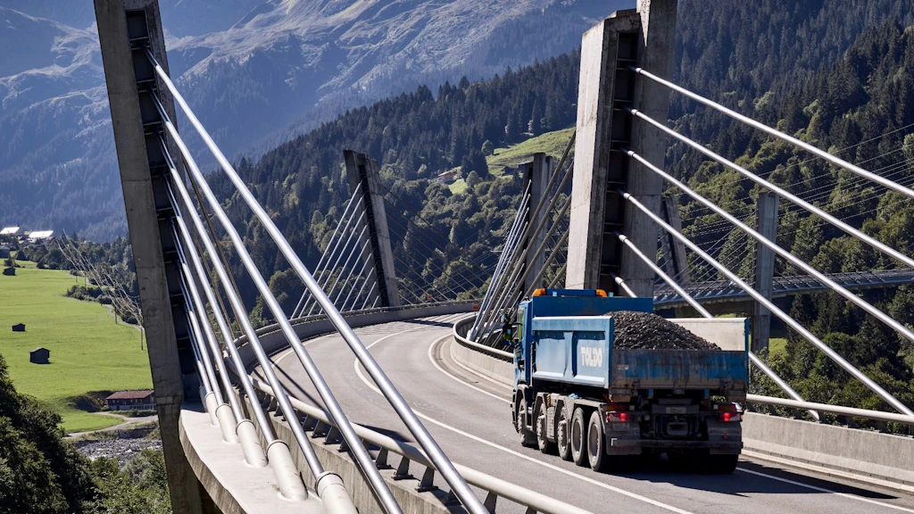 Un camion si dirige sul ponte Sunniberg verso un paesaggio di montagna. L’immmagine trasmette un’atmosfera di partenza.